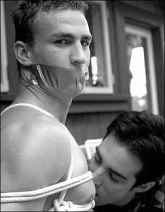 En bunden man med munkavle och en annan man som kysser hans hud
